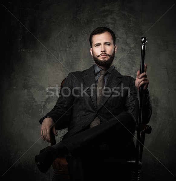 Stock photo: Handsome well-dressed man with walking stick sitting in leather chair 