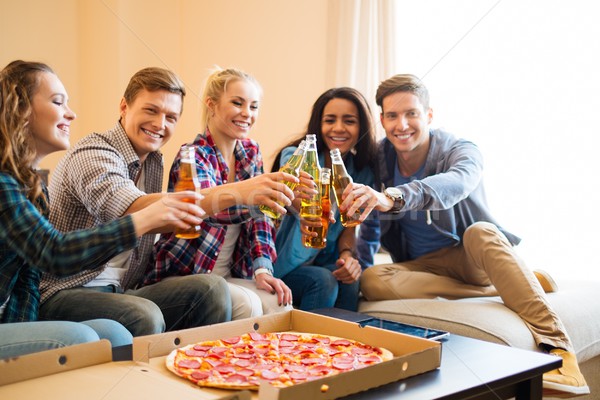 Multi-ethnic friends with pizza and bottles of drinks having party Stock photo © Nejron