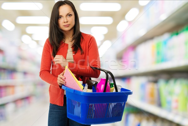 Beautiful cheerful brunette woman with basket full of cleansers in a shop Stock photo © Nejron