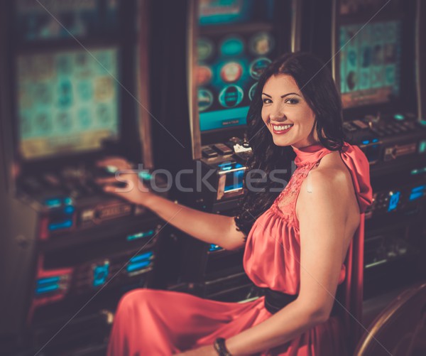 Bela mulher vestido vermelho jogar caça-níqueis dinheiro feliz Foto stock © Nejron