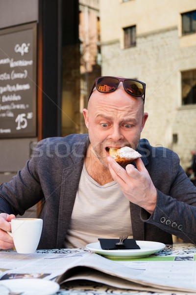 Surprised middle-aged man reading newspaper behind table in street cafe during coffee pause Stock photo © Nejron