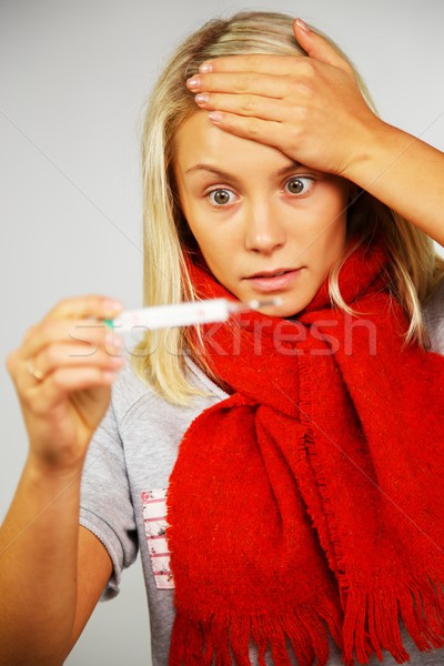 Sick young woman looking at thermometer  Stock photo © Nejron
