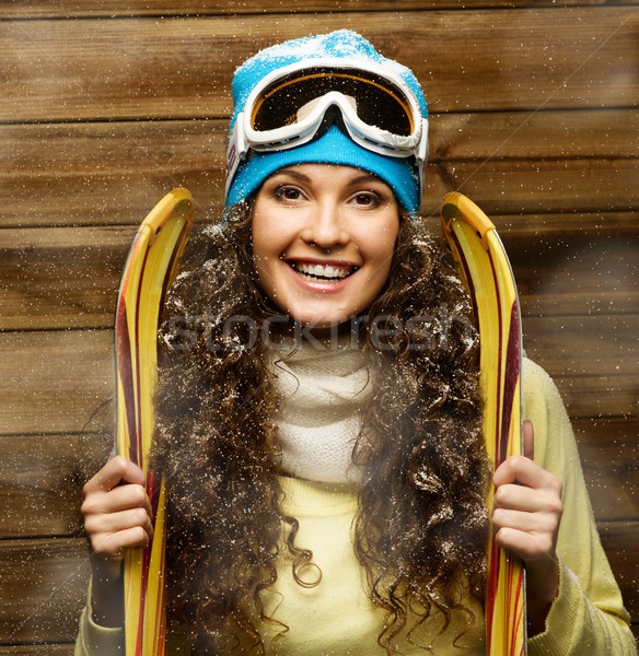 Smiling woman with skies standing against wooden house wall under snow Stock photo © Nejron