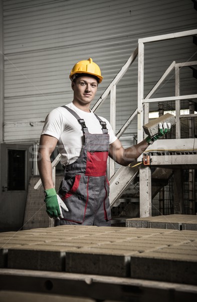Young worker near conveyor belt with paving stone on a factory   Stock photo © Nejron