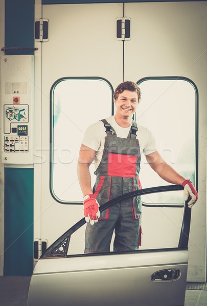 Cheerful serviceman with car door near paint booth in a car body workshop Stock photo © Nejron