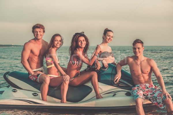 Group of happy multi ethnic friends sitting on a jet ski Stock photo © Nejron
