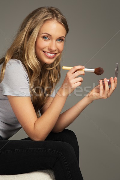 Positive young woman with long hair applying blushes  Stock photo © Nejron