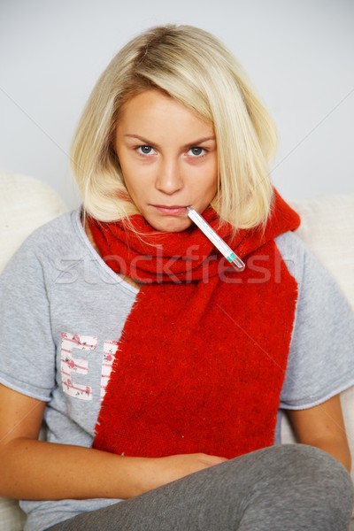 Stock photo: Sick young woman with thermometer at home