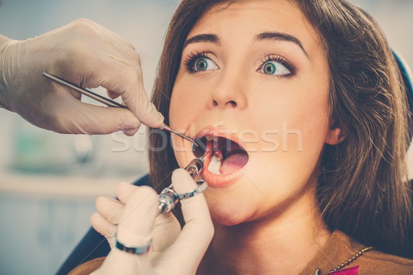 Dentist making anaesthetic injection to scared female patient  Stock photo © Nejron