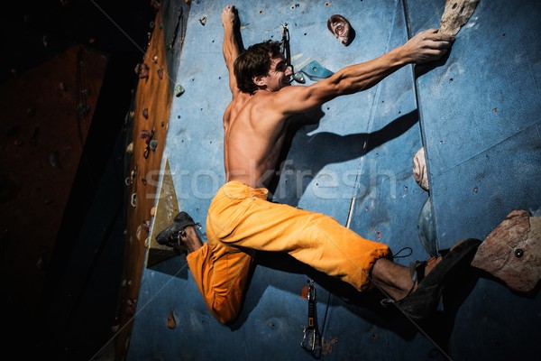 Muscular man practicing rock-climbing on a rock wall indoors  Stock photo © Nejron