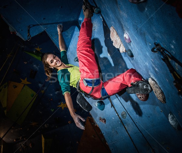 Young woman practicing rock-climbing on a rock wall indoors Stock photo © Nejron