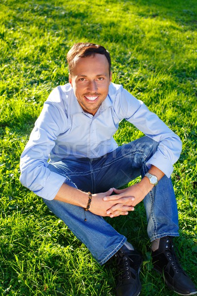 Happy handsome middle-aged man sitting on a grass outdoors  Stock photo © Nejron
