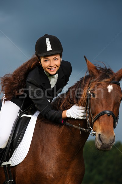 Stock photo: Beautiful girl sitting on a horse outdoors against moody sky