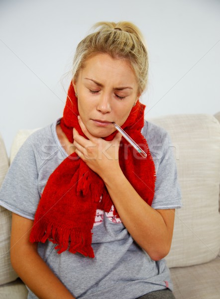 Stock photo: Sick young woman with thermometer at home