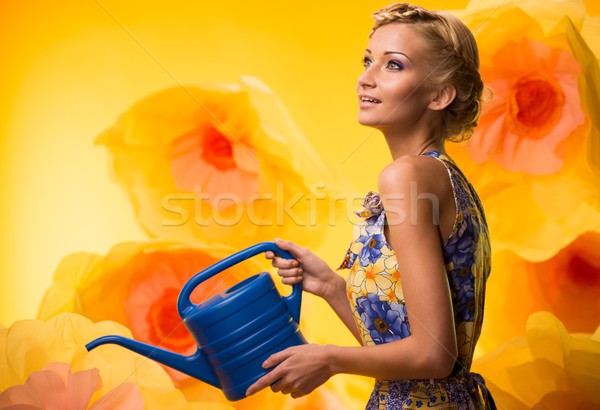 Beautiful dreaming woman in colourful dress with watering can among big yellow flowers Stock photo © Nejron