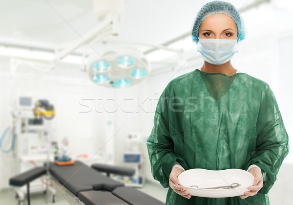 Young woman doctor in cap and face mask holding medicine tray with surgery tools  Stock photo © Nejron