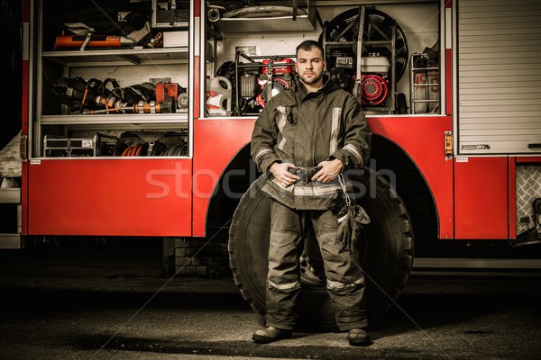 Cheerful firefighter near truck with equipment  Stock photo © Nejron