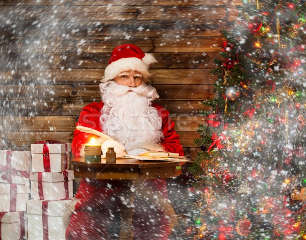 Santa Claus in wooden home interior sitting behind table and writing letters with quill pen Stock photo © Nejron