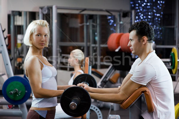 Handsome young man lifting weights assisted by a female trainer Stock photo © Nejron
