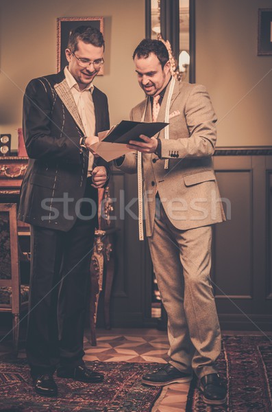 Stock photo: Tailor and client choosing cloth and buttons for custom made suit 