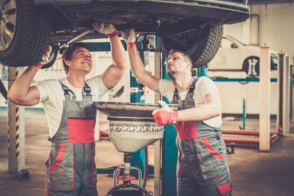 Two mechanics changing oil  in a car workshop Stock photo © Nejron