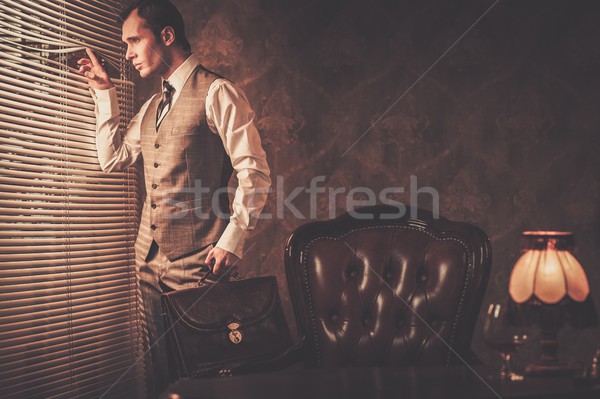 Well-dressed man with a briefcase looking through jalousie  Stock photo © Nejron