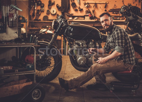 Stock photo: Mechanic building vintage style cafe-racer motorcycle  in custom garage