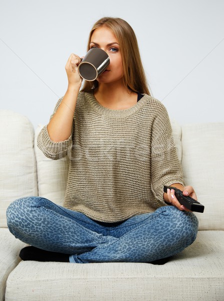 Young beautiful woman on a sofa with remote control and mug Stock photo © Nejron