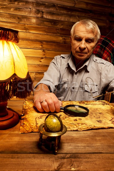 Senior man with magnifier looking at vintage map in homely wooden interior  Stock photo © Nejron