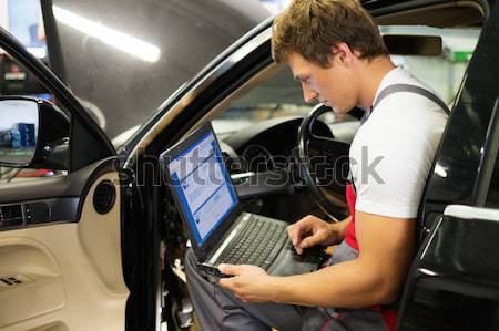Serviceman making car diagnostics with laptop in a workshop Stock photo © Nejron