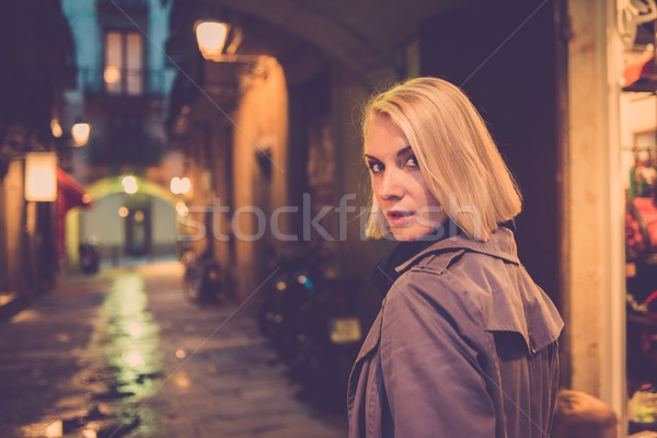 Beautiful blond woman in raincoat walking alone outdoors at night Stock photo © Nejron