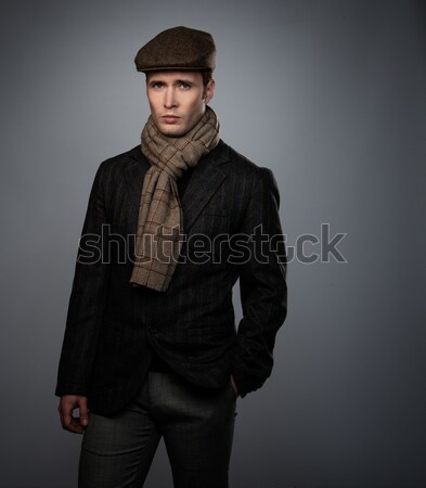Young man in brown jacket wearing cap and scarf isolated on grey background  Stock photo © Nejron