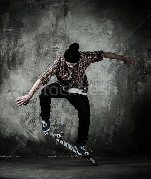Young man in hat and shirt performing stunt on skateboard Stock photo © Nejron