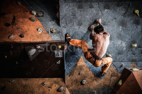 Muscular man practicing rock-climbing on a rock wall indoors  Stock photo © Nejron