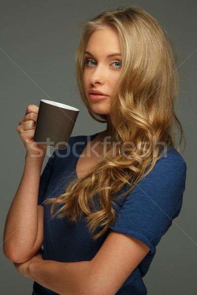 Positive young woman with long hair and blue eyes holding cup Stock photo © Nejron