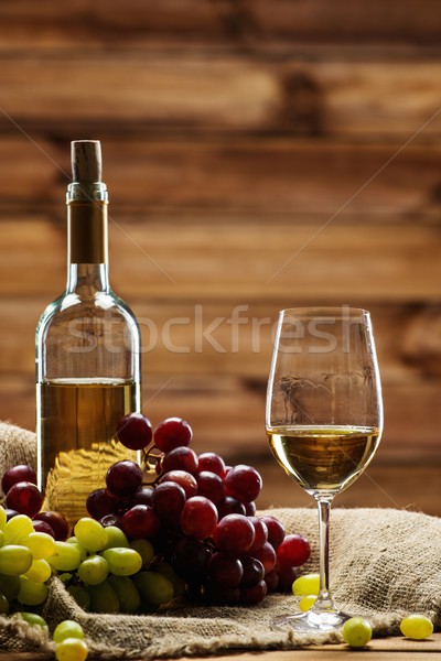 Bottle of red white, glass and grape on a sack in wooden interior  Stock photo © Nejron