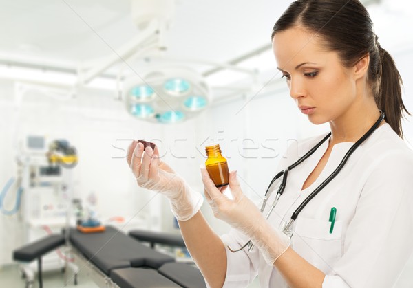 Young doctor woman reading prescription on a vial in surgery interior Stock photo © Nejron