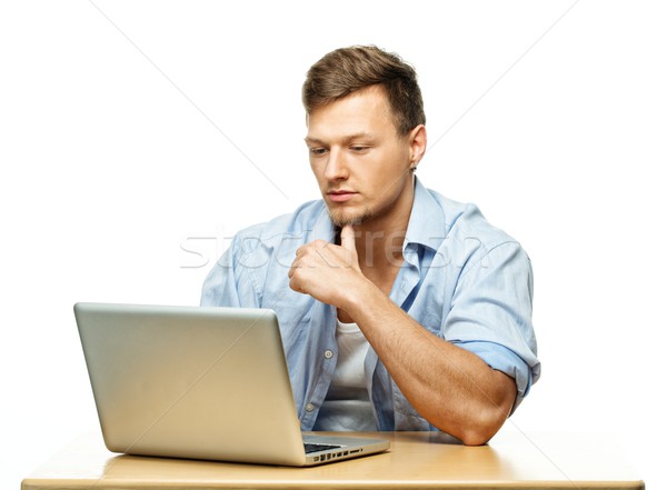 Stock photo: Concentrated stylish young man behind laptop isolated on white 