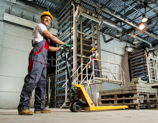Young worker moving paving stones with pallet truck on a factory Stock photo © Nejron