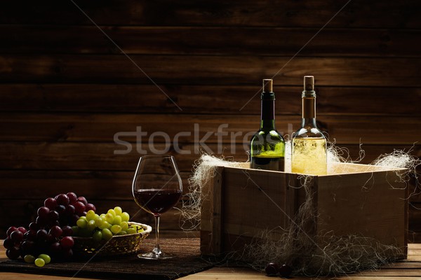 Bottles of red and white wine, glass and grape on a wooden interior  Stock photo © Nejron