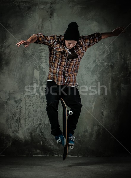Young man in hat and shirt performing stunt on skateboard Stock photo © Nejron