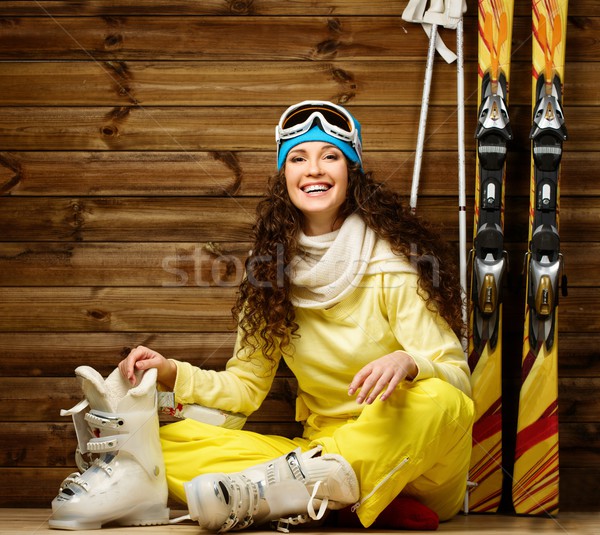 Happy woman with skis and ski boots sitting on a floor near wooden wall Stock photo © Nejron