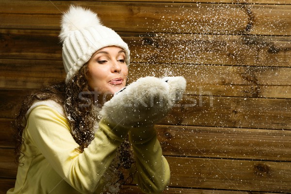 Beautiful woman in knit hat blowing snow from her hands Stock photo © Nejron
