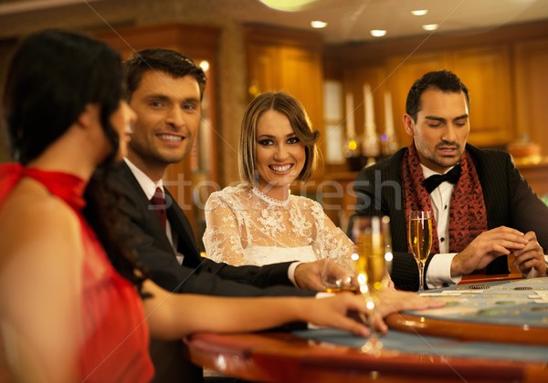 Group of happy young people behind gambling table with drinks Stock photo © Nejron