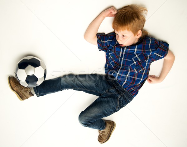 Little funny redhead boy kicking soccer ball Stock photo © Nejron