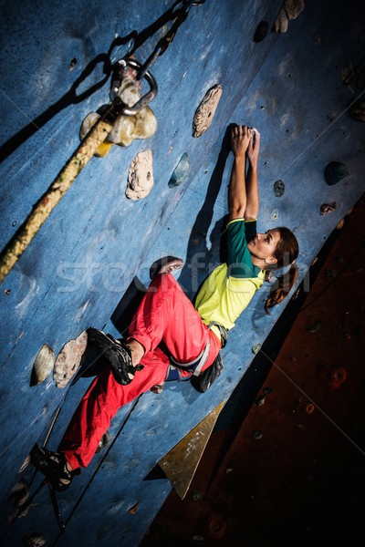 Young woman practicing rock-climbing on a rock wall indoors Stock photo © Nejron