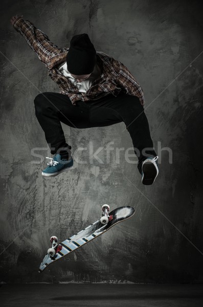 Young man in hat and shirt performing stunt on skateboard Stock photo © Nejron