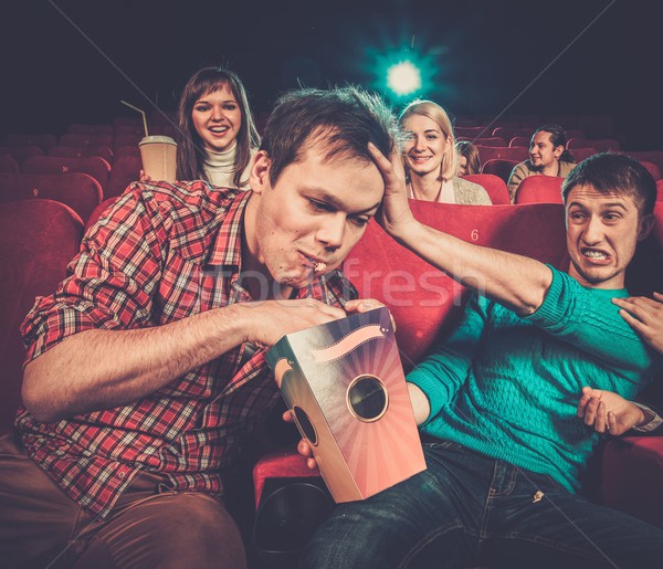 Impudent young man steals popcorn in cinema while people watching movie Stock photo © Nejron