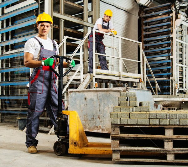 Young worker moving paving stones with pallet truck on a factory Stock photo © Nejron