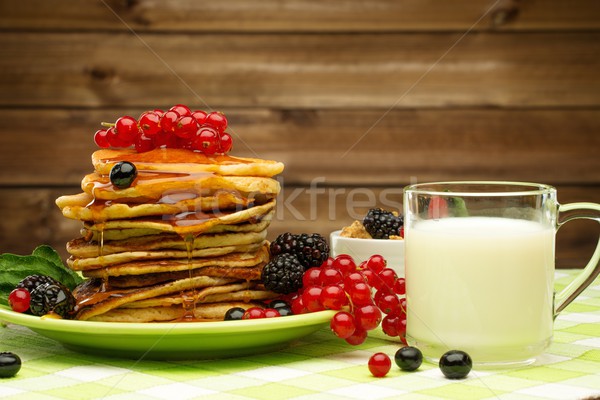 Healthy breakfast with pancakes, fresh berries and milk on tablecloth in rural interior  Stock photo © Nejron